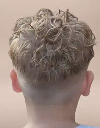 Back view of a person with short, curly blonde hair and a faded undercut, against a plain background.