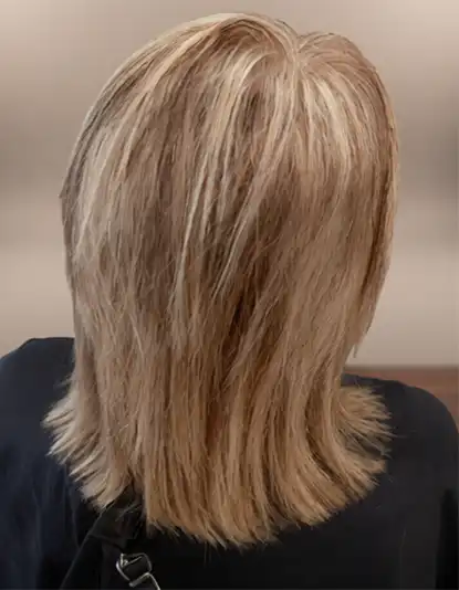 A person with layered, shoulder-length blonde hair seen from the back, wearing a dark-coloured top.