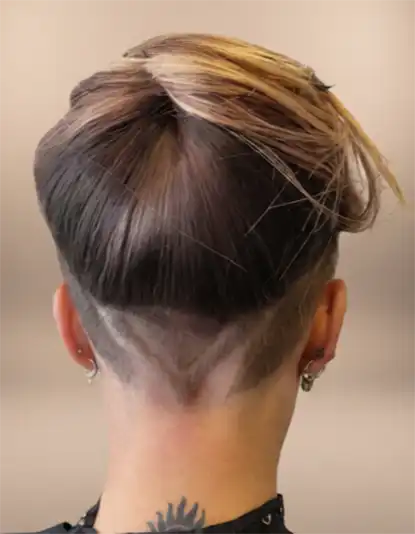 A back view of a person with an undercut hairstyle, featuring a V-shaped shaved design and longer hair on top.
