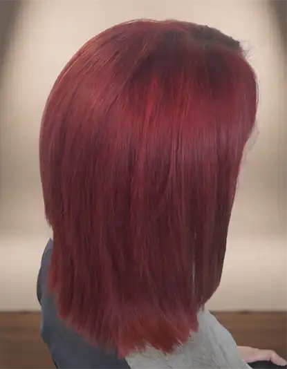 A person with straight, shoulder-length, vibrant red hair facing slightly away from the camera.