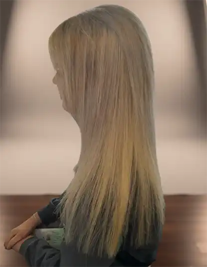 A woman with long, straight blonde hair standing in profile against a blurred background.