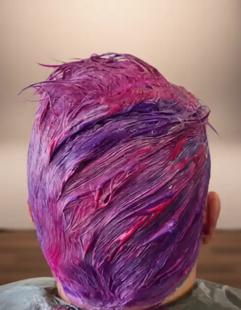 Back view of a person's head with wet, freshly dyed hair in shades of pink, purple, and red.